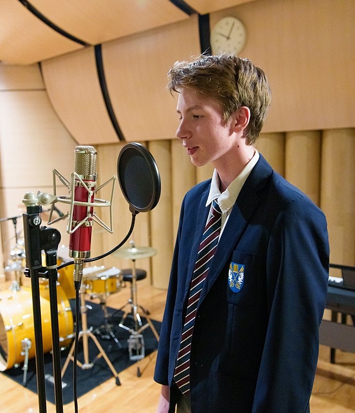  Boy playing guitar during after-school club at Brighton College Vibhavadi, building confidence through performing arts education. 