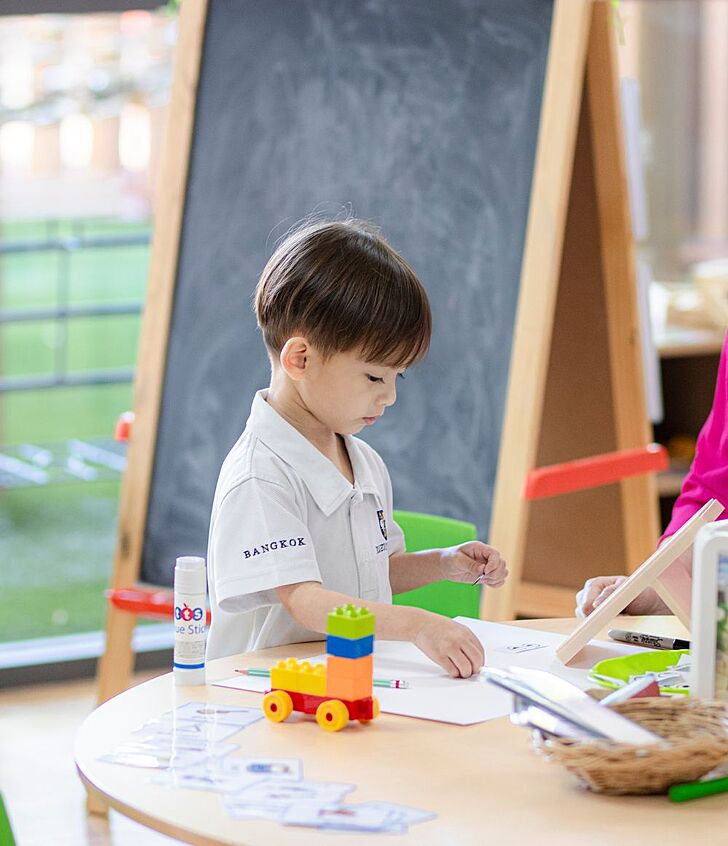  Nursery pupil placing a sticker during an activity at Brighton College Vibhavadi, supporting fine motor skills and early development through playful learning. 