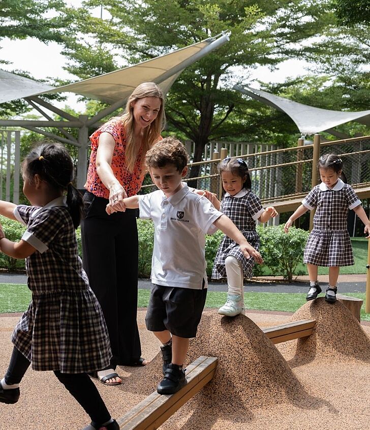  Teacher holding a pupil’s hand and smiling at Brighton College Vibhavadi, showing caring relationships in a supportive school environment. 