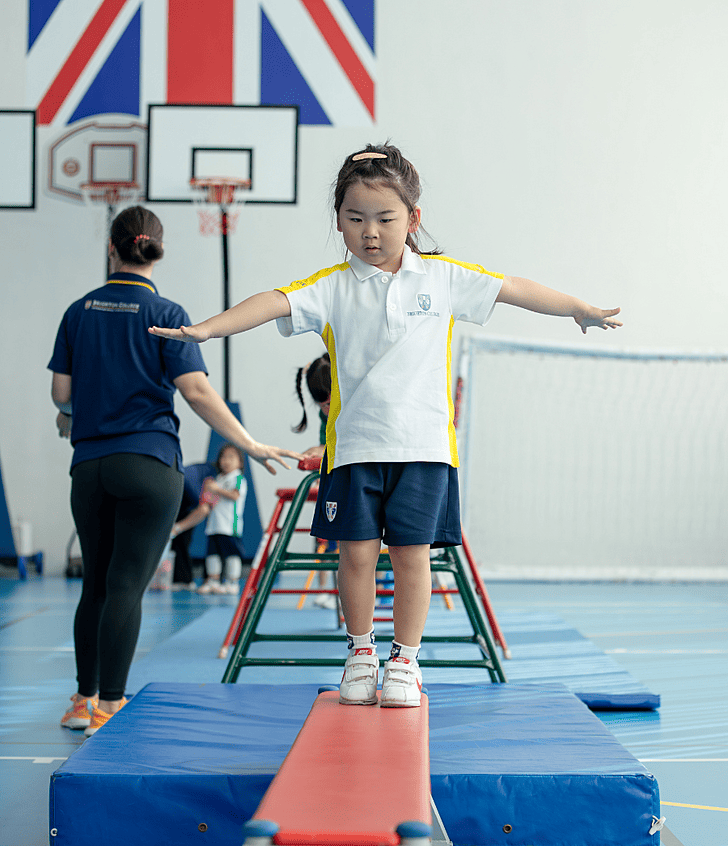  Prep pupil balancing in sports hall at Brighton College Krungthep Kreetha, enjoying physical activity beyond the classroom. 